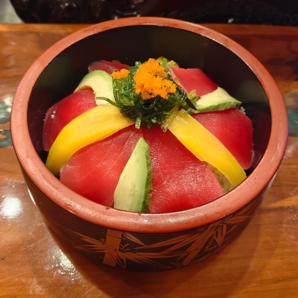 A colorful Asian Arch chirashi bowl with tuna, avocado, mango, seaweed, and orange roe.