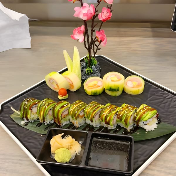 Asian Arch sushi platter with avocado rolls, cucumber-wrapped rolls, ginger, wasabi, and a floral decoration.